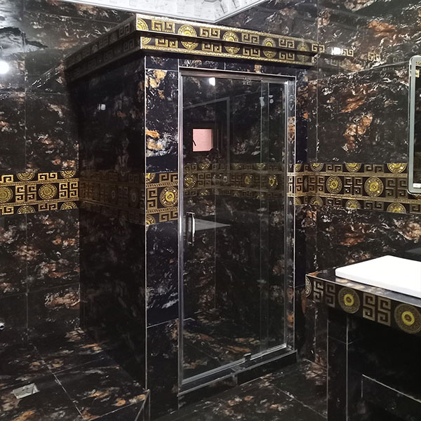 Badezimmer mit edler Steinoberfläche und exklusiver Wandgestaltung. Schwarz und gold.